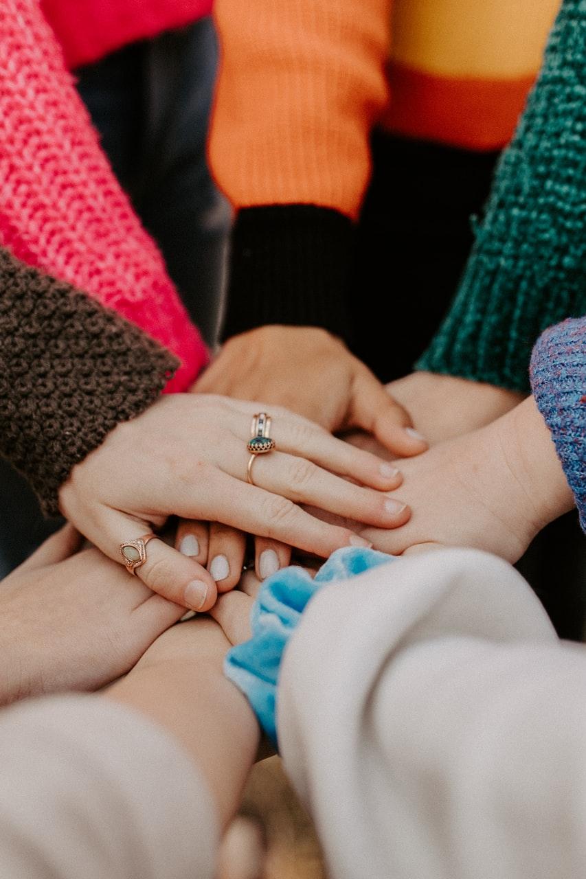 person in red sweater holding babys hand